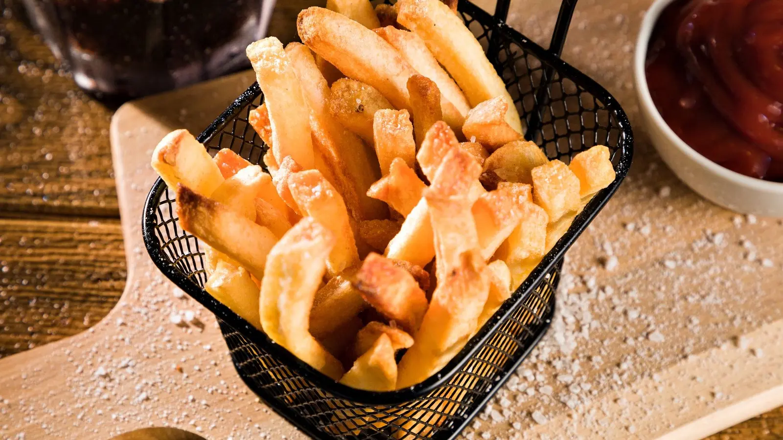 Basket of golden French fries on a wooden board